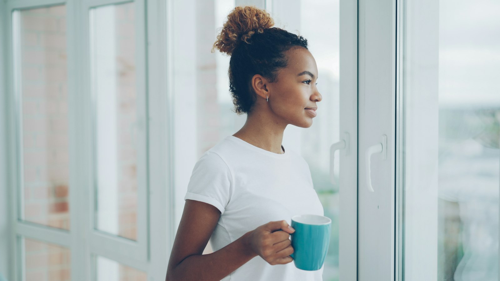 Woman holding a mug and looking out a window